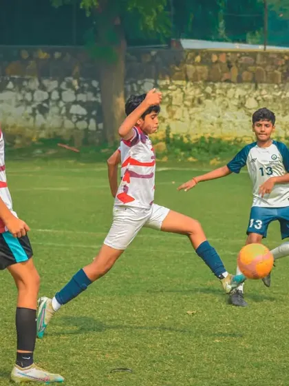 A player stretches to get a foot on the ball before his opponent.