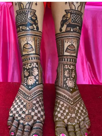 A bold foot mehendi design with elephants and jhumkas on the ankles and a dense jaali pattern on the feet.