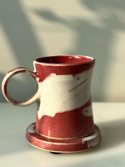 A single mug and coaster from the Flamingo series, highlighting the unique, flowing pattern of the glaze.