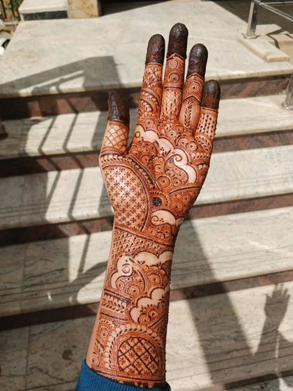 This is a full bridal mehendi I practiced on myself, inspired by one of my favorite artists. It features cloud-like swirls, intricate netting, and varied finger designs, covering the hand and arm completely.