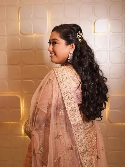 A side profile showcasing the romantic, half-up hairstyle. This is a popular choice for receptions and sangeets as it is both elegant and comfortable.