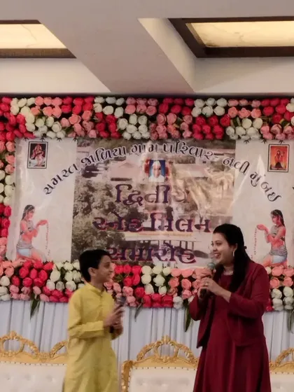 Sharing a laugh with a young participant on stage at a Gujarati community event. My ability to host in Gujarati makes me a preferred emcee for these cultural functions.