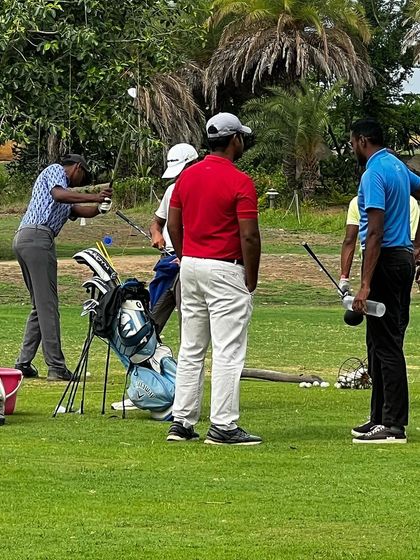 A group of coaches observing a player on the short game area. This collaborative approach ensures every player gets the best possible guidance.