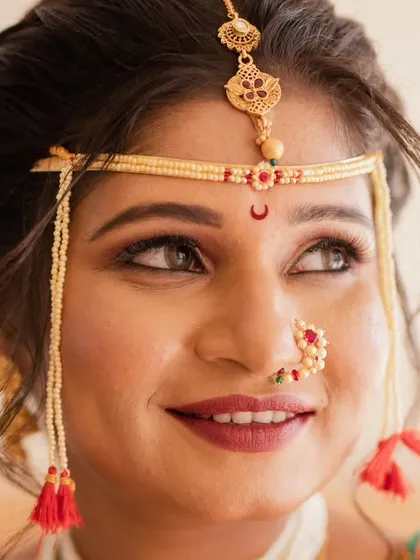 A detailed look at a traditional Maharashtrian bridal makeup. The focus is on the eyes, defined to stand out, and the classic half-moon bindi and ornate 'mundavalya' that complete this iconic look.