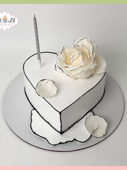A minimalist and artistic heart-shaped cake. This "comic book" style cake features black outlines and a single, beautifully crafted white sugar rose.