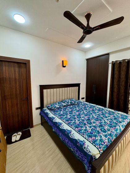 A wider view of the bedroom, showing the placement of the bed, wardrobe, and the matching wooden door, creating a harmonious look.