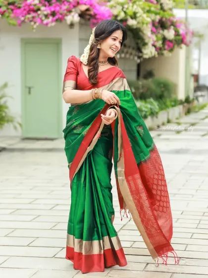 A full-length shot showing the elegant drape of the saree. The bride's pose is graceful, and the outdoor setting adds a touch of natural beauty.