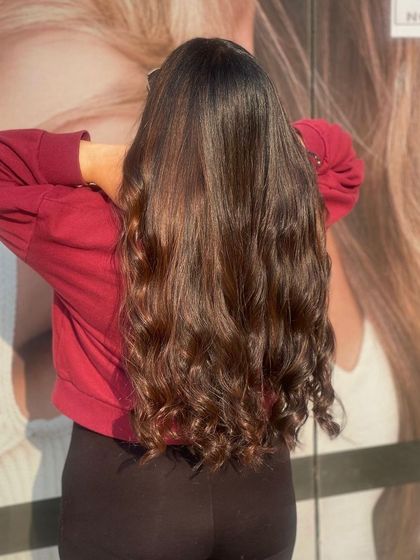 This client's long, dark hair is styled into beautiful, bouncy curls at the ends, showing off the health and shine of her hair after a salon service.