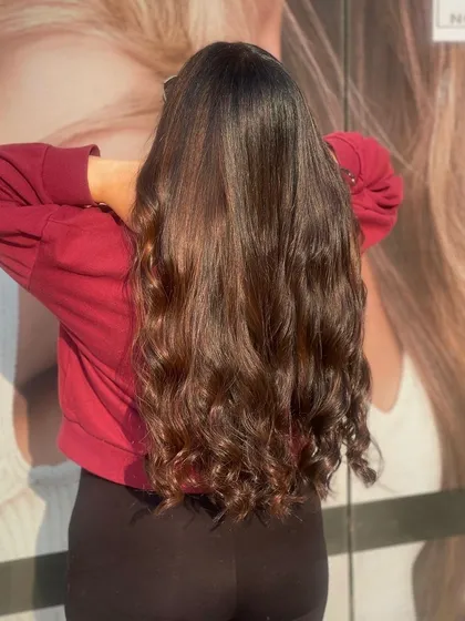 This client's long, dark hair is styled into beautiful, bouncy curls at the ends, showing off the health and shine of her hair after a salon service.