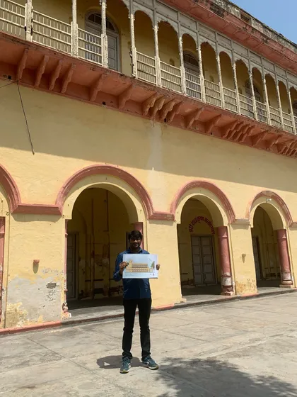 A team member holding up a plan against the backdrop of the haveli's grand facade, symbolizing the beginning of a meticulously planned restoration journey.