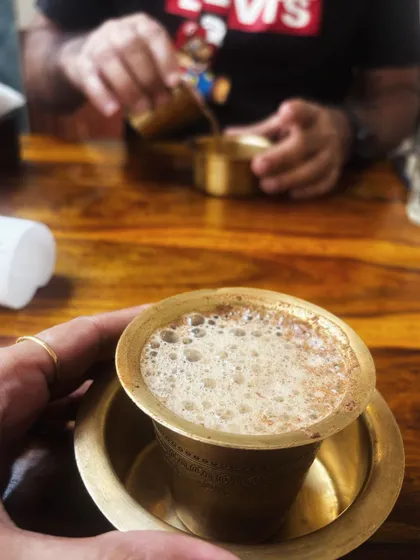 A close-up of a traditional South Indian filter coffee in a brass cup, showcasing an authentic cultural experience.
