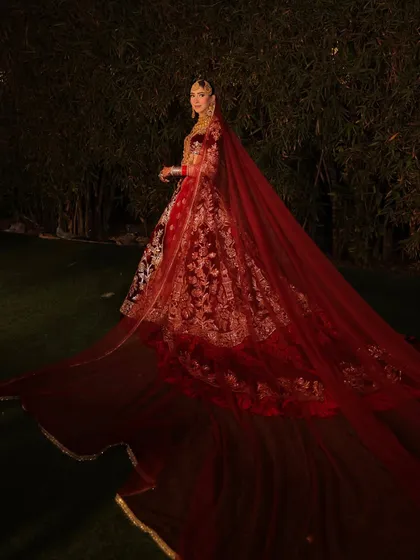 A bride's entry is a story in itself. This breathtaking full-length shot captures the grandeur of a deep red velvet lehenga with a magnificent trail, a look I created to be as epic and memorable as the day itself.