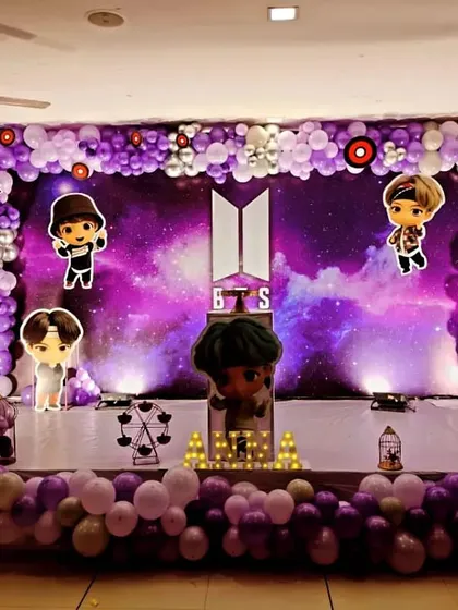 A BTS theme birthday decoration for a K-pop fan, with a galaxy backdrop, character cutouts, and a purple and silver balloon frame.