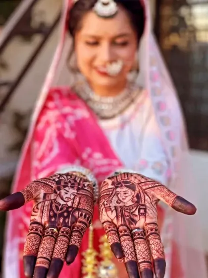 A bride happily showing her couple portrait mehndi. The dark, rich stain makes the faces of the bride and groom stand out beautifully.