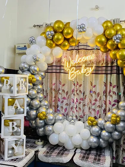 A slightly different perspective of the gold and silver 'Welcome Baby' balloon ring, showing how it can transform a living room corner.