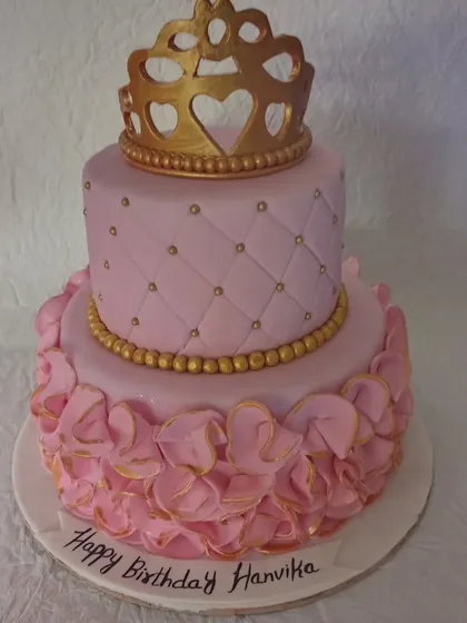 A still image of the beautiful two-tiered pink princess cake, highlighting the intricate ruffle details on the bottom tier and the sparkling gold accents.
