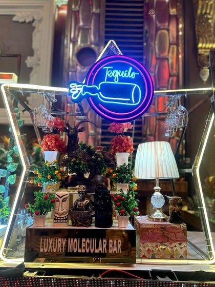 A full view of our star-shaped 'Tequila' station, intricately decorated with plants, tiki mugs, and a glowing neon sign.