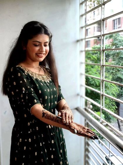 A client admiring her mehandi in natural daylight, which brings out the beautiful details of the design on her arm.