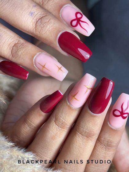 A cute and bold design featuring cherry red polish with hand-painted bow art on a pink base. This is a playful and stylish take on red nails, perfect for making a statement.