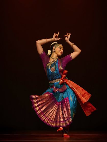 A graceful pose from 'Viśvambhara', a performance that explores the cosmos. The vibrant costume and intricate movements come together to create a visual spectacle for the audience.