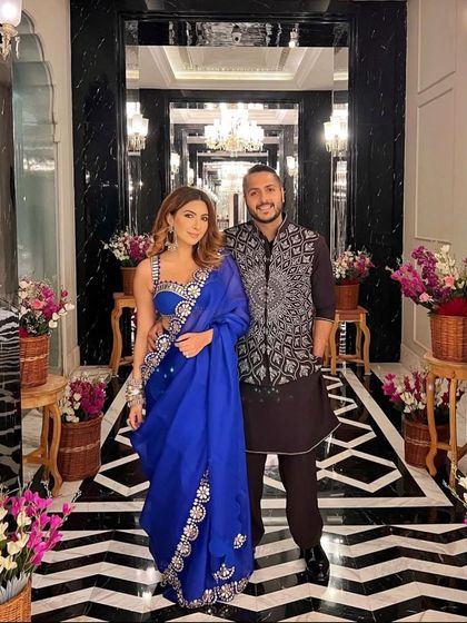 A happy couple posing in the grand floral entryway we designed. Our decor creates the perfect backdrop for capturing beautiful memories of your special day.