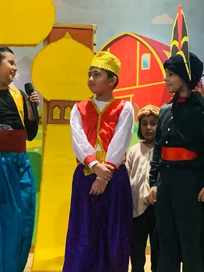 The cast of the Aladdin show interacts on stage during a key moment in the story.