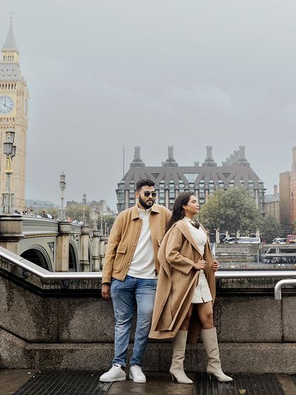 Posing with the iconic Big Ben in the background. Their coordinated trench coats and chic styling make for a classic London pre-wedding portrait.