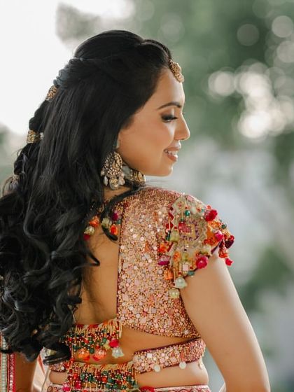 A close-up of the back of Nikita's blouse and her half-tied hairstyle, accented with colorful gotta to match the details on her lehenga.
