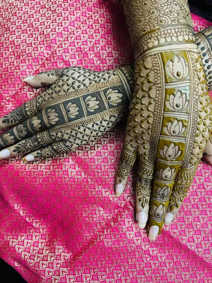 This is a popular backhand design featuring a lotus motif. You can see the difference here between the fresh henna paste on one hand and the developing stain on the other.