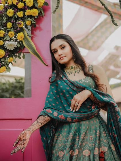 A stylish pose by a beautiful bride, her mehandi-adorned hand resting gracefully.