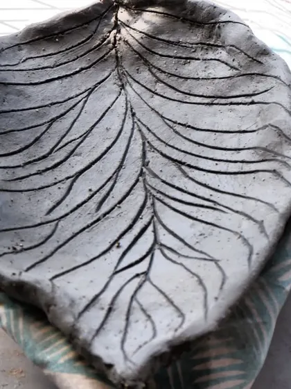 A hand-built leaf tray with carved veins. This piece is waiting to be transformed by the fire and smoke of the Raku kiln.