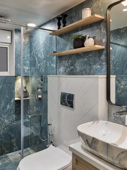 The powder bathroom of Apartment 1101 is simple yet elegant, featuring beautiful aqua marble finish tiles. On the ledge wall, classic white subway tiles and charming wooden shelves create a captivating contrast.