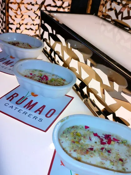 A classic Indian dessert, Phirni or Kheer, served in individual bowls. Garnished with pistachios and rose petals, it's a comforting and elegant end to any meal.