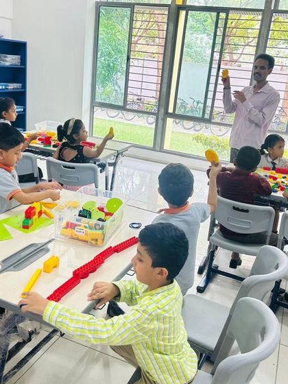 A vibrant classroom scene at The School for Global Minds, where students are actively engaged in a hands-on LEGO lesson.