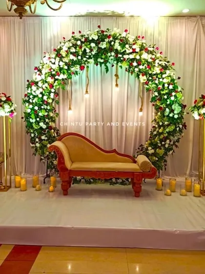 A beautiful floral ring stage for a Christian wedding reception. This elegant setup uses a full circle arch of white and red roses, complemented by warm lighting and candles to create a romantic ambiance.