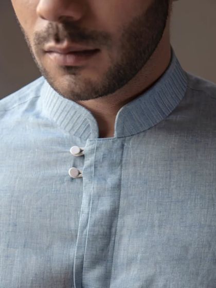 A close-up on the mandarin collar and button placket of the blue linen shirt. The details are subtle but thoughtfully designed.