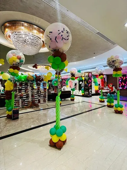 Themed balloon pillars designed to look like sweet treats or trees, adding height and color to the jungle party space.