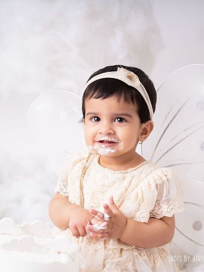 A close up of the messy, happy face. The simple, all white theme puts all the focus on her adorable expressions and the fun she's having.