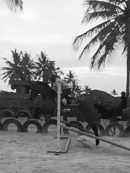 A black and white shot of a rider clearing a jump, highlighting the timeless elegance and power of the equestrian sport.
