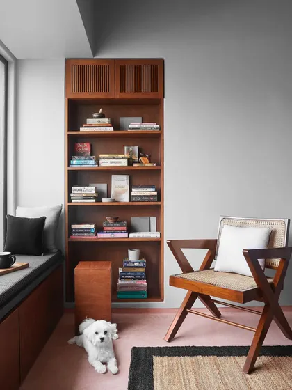 A cozy corner with a built-in window seat and a classic armchair. I design these spaces as quiet retreats for reading or enjoying a cup of tea, complete with custom shelving for books.
