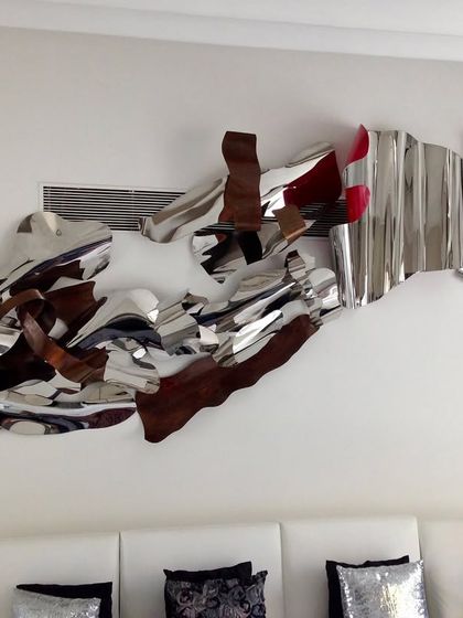 A throwback to a large, 12-foot installation from 2017. This piece combines polished steel with wood-textured and red elements for a complex, abstract composition.