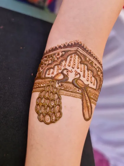 A close-up of a delicate peacock armlet, a beautiful and elegant addition to any bridal mehendi design.