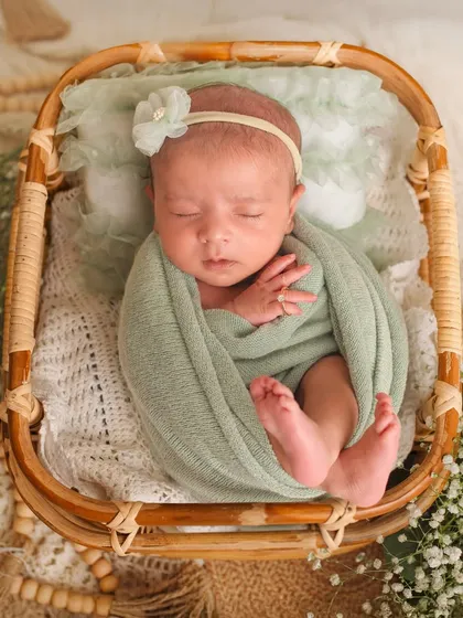 A top-down view of a newborn swaddled in a basket. This pose, often called the "potato sack," is a safe and adorable way to photograph newborns.