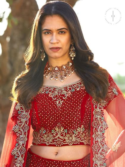 A detailed close-up of the bridal red lehenga's blouse. You can see the exquisite beadwork and embroidery that make this piece so special. It’s all about those luxurious details.