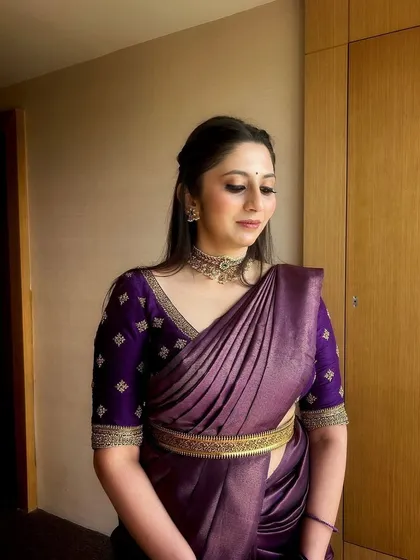 A client looking elegant in a deep purple saree. Her custom blouse features simple butti embroidery and a finely detailed border on the sleeves, perfect for a wedding guest look.