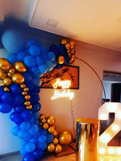 A bold and stylish 2nd birthday setup. We combined a royal blue and gold chrome balloon arch with a 'Happy Birthday' neon sign and a large light-up number '2' to create a vibrant and celebratory corner.