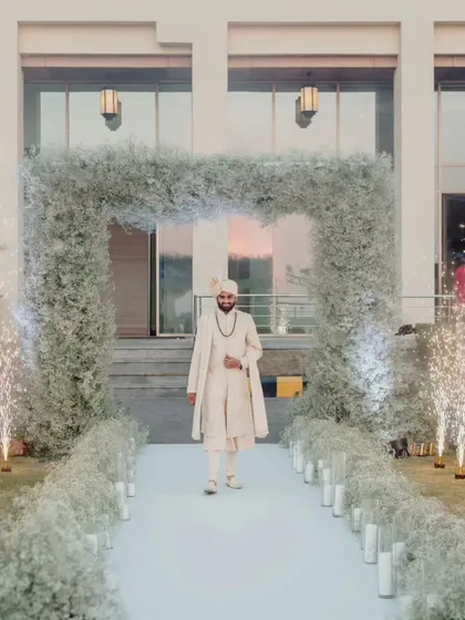 The groom makes his solo entrance down an aisle lined with baby's breath and cold pyros. A stylish and confident start to the wedding ceremony.