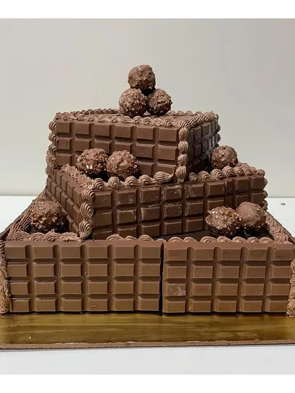 Another angle of the 3-tier square chocolate cake. This view shows the rich texture of the Cadbury chocolate bars and Ferrero Rocher toppings.