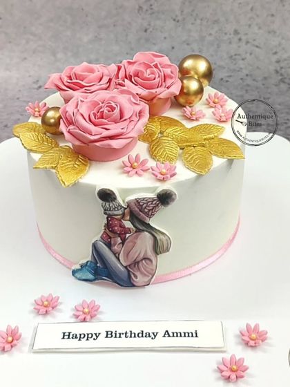 A sweet "Supermom" cake featuring a touching illustration of a mother and child. The cake is adorned with pink roses and golden leaves, making it a perfect birthday gift for Ammi.