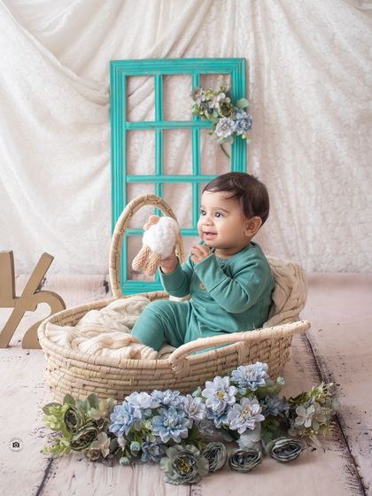 Celebrating six months with a half-birthday shoot. This little one is all smiles in a wicker basket, with a "1/2" sign and a lovely blue floral theme.